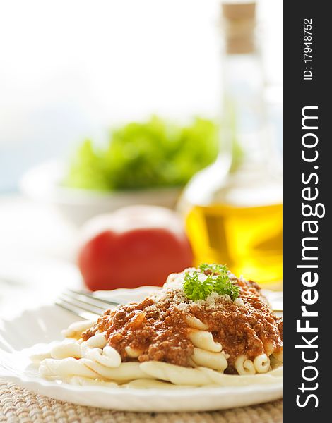 Pasta with bolognese sauce and olive oil and salad in the back