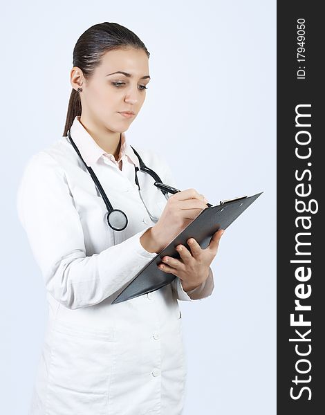 Portrait of friendly female doctor with stethoscope writes on the clipboard. Portrait of friendly female doctor with stethoscope writes on the clipboard.