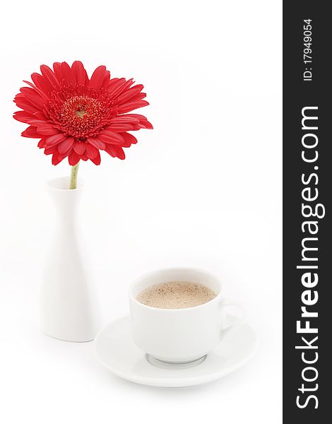 Red gerbera in vase near cup of coffee on a table isolated on white. Red gerbera in vase near cup of coffee on a table isolated on white