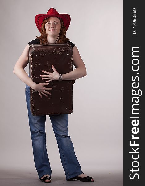 The girl in a red hat with old suitcases in hands on a gray background. The girl in a red hat with old suitcases in hands on a gray background