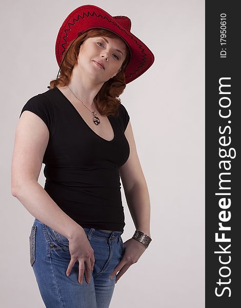 Portrait of the woman in a red cowboy's hat on a gray background