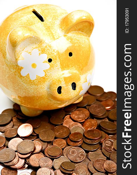 Yellow ceramic piggy bank on a pile of cents, isolated on white