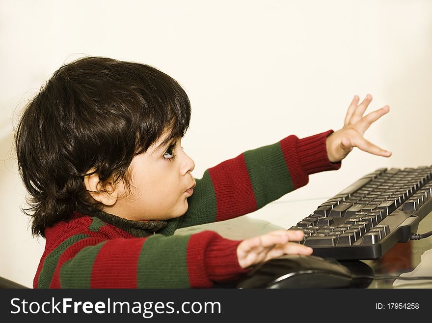 A cute little child working on his PC. A cute little child working on his PC.