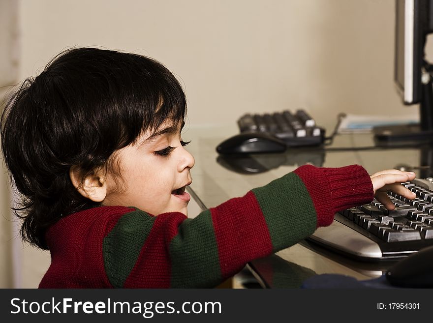 A cute little boy eating cookies and working on his PC. A cute little boy eating cookies and working on his PC.