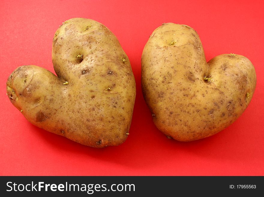 Two potatoes in the shape of a heart on a red background. Two potatoes in the shape of a heart on a red background