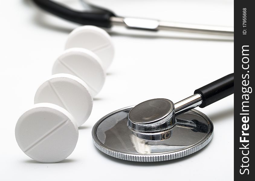 Stethoscope and white tablets on white