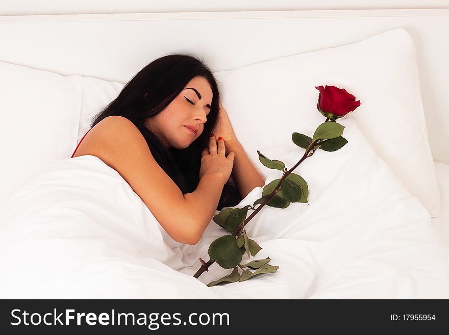 A beautiful young girl lying in bed with gifts, roses, woke up, asleep.