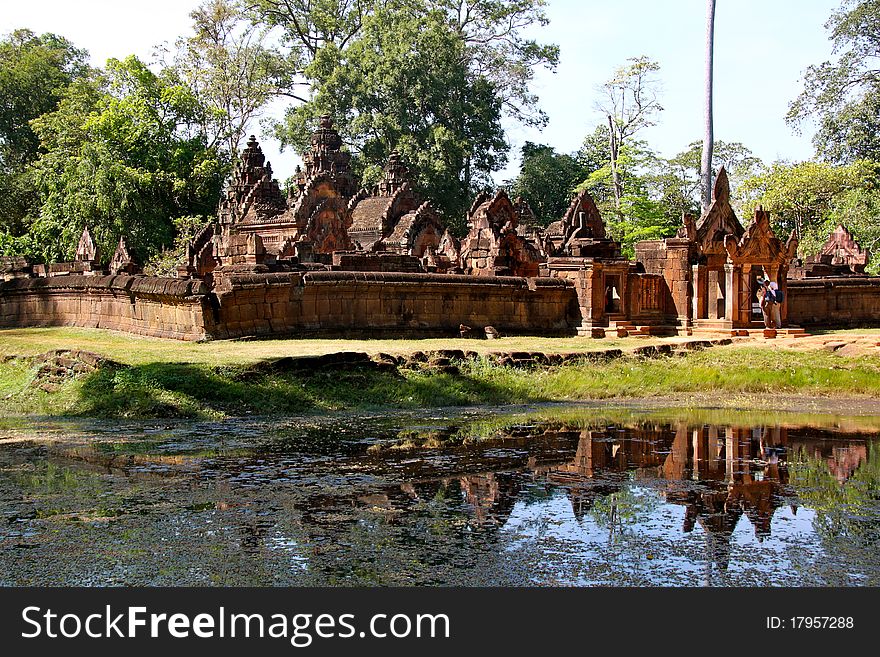 Located 20km (12mi) north of Angkor, this small but exquisite little jewel of a temple was built by Yajnavaraha, an official of Rajendravarman (944-968) and guru of Jayavarman V (968-1000). As if to make up for its diminutive size (the first, inner, enclosure is a mere 24m, about 80', square), Banteay Srei (pronounced BAHN-tay SHREE) is carved on every square inch with outstanding fineness and detail.
The temple's second enclosure with gopura is seen here, from just slightly north of east, reflected in the surrounding moat. Located 20km (12mi) north of Angkor, this small but exquisite little jewel of a temple was built by Yajnavaraha, an official of Rajendravarman (944-968) and guru of Jayavarman V (968-1000). As if to make up for its diminutive size (the first, inner, enclosure is a mere 24m, about 80', square), Banteay Srei (pronounced BAHN-tay SHREE) is carved on every square inch with outstanding fineness and detail.
The temple's second enclosure with gopura is seen here, from just slightly north of east, reflected in the surrounding moat.