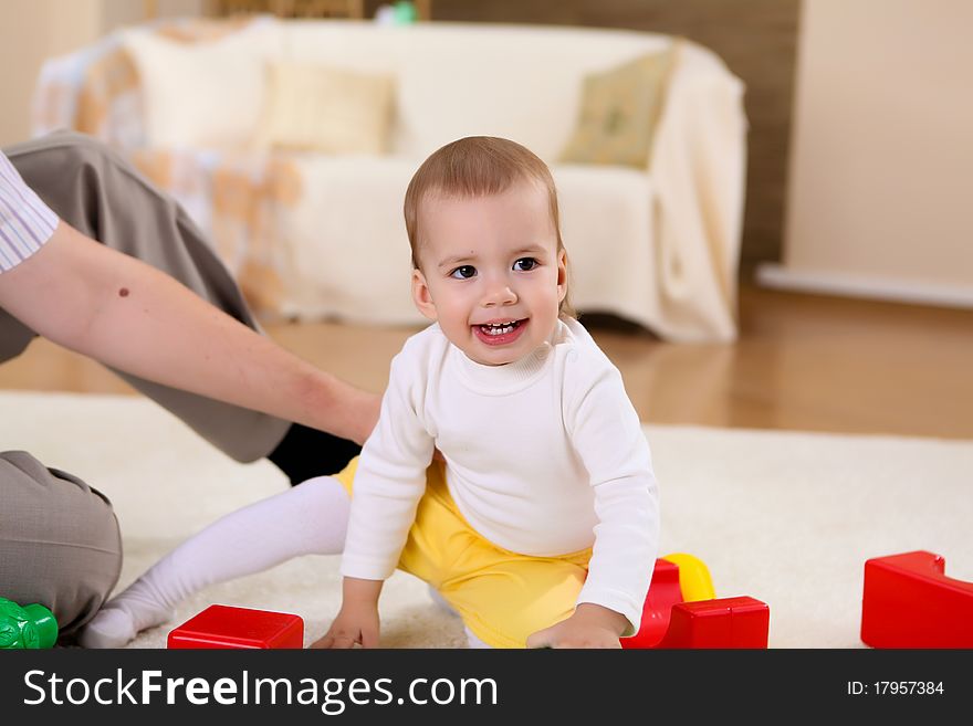 Young happy family playing with a baby in the living-room. Young happy family playing with a baby in the living-room