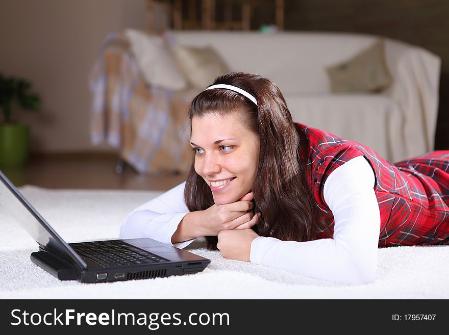 A young girl with a lap top at home on the floor of a living room