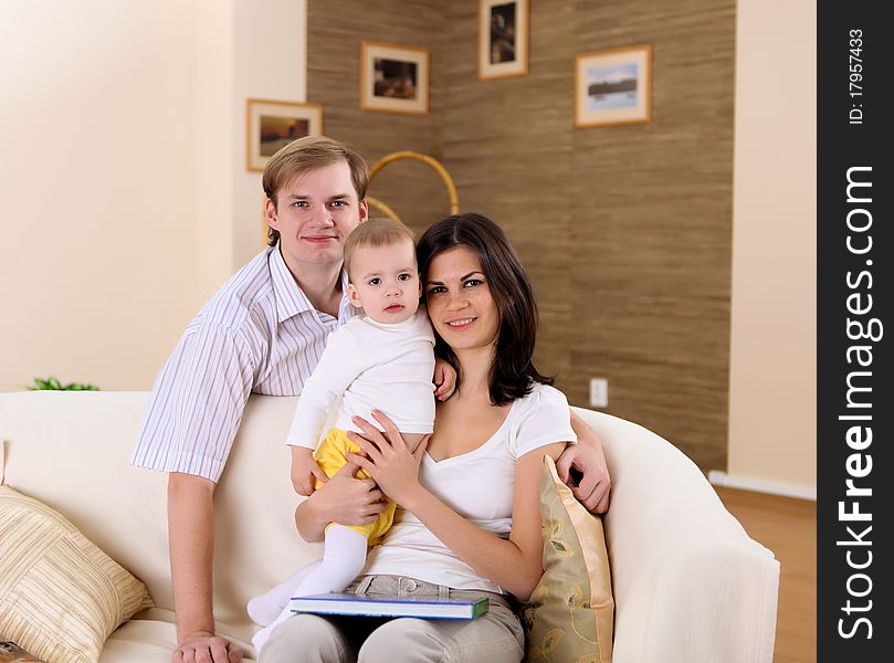 Young happy family playing with a baby in the living-room. Young happy family playing with a baby in the living-room