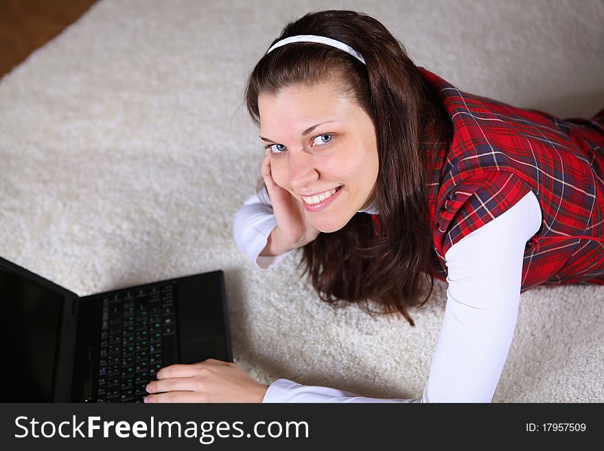 A young girl with a lap top at home on the floor of a living room