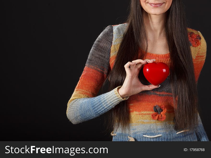 Young female holding heart shape on dark background. Young female holding heart shape on dark background