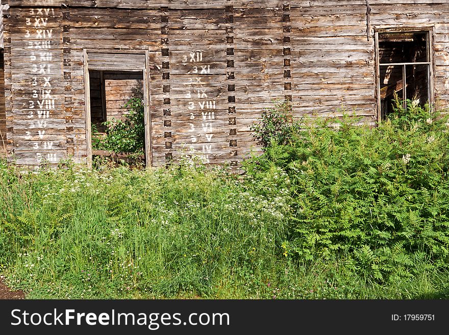 An abandoned rural wooden house, in a serious state of disrepair with numbers on the wall. An abandoned rural wooden house, in a serious state of disrepair with numbers on the wall