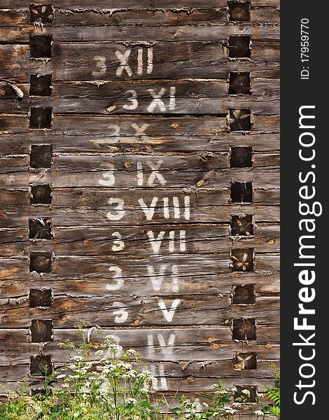 Wooden wall with written arabic and roman numbers in logs in order. Wooden wall with written arabic and roman numbers in logs in order
