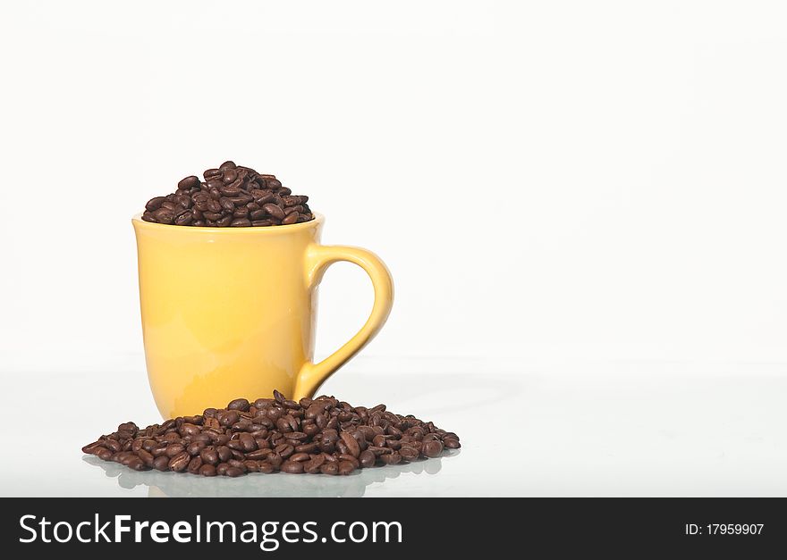 Still life of roasted coffee beans in a yellow earthenware mug. Still life of roasted coffee beans in a yellow earthenware mug