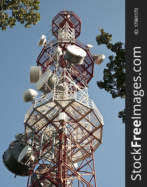 Huge communication antenna tower and satellite dishes against blue sky. Huge communication antenna tower and satellite dishes against blue sky