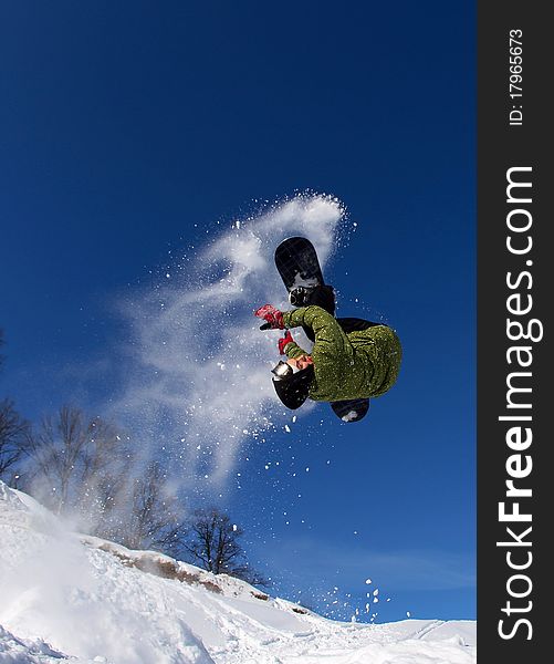 Snowboarder jumping frontflip through air with deep blue sky in background. Snowboarder jumping frontflip through air with deep blue sky in background