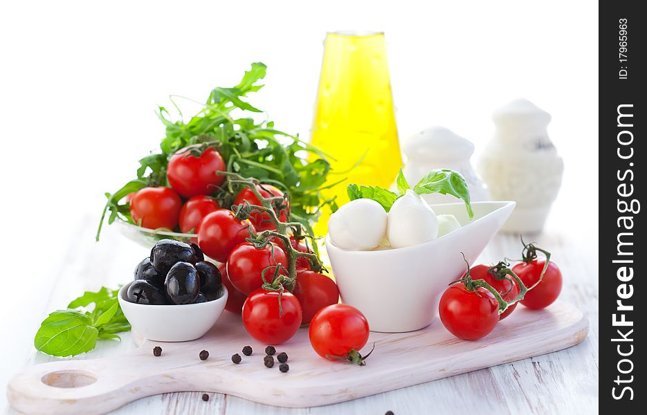 Ingredients for salad with mozzarella, tomatoes,black olives,rocket and olive oil. Ingredients for salad with mozzarella, tomatoes,black olives,rocket and olive oil