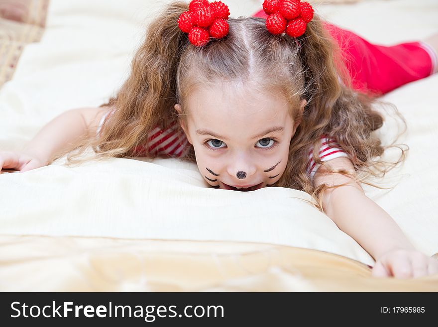 A funny girl is portraiting a kitten is lying on the bed. A funny girl is portraiting a kitten is lying on the bed