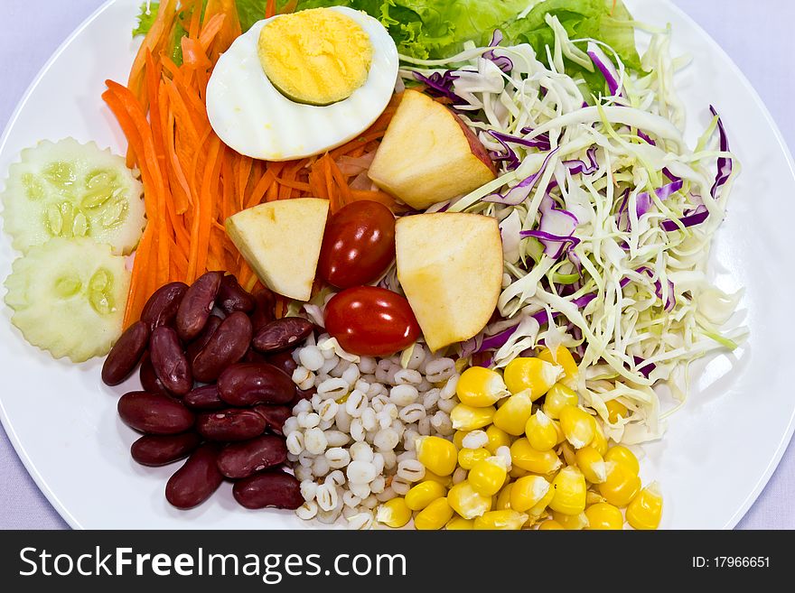 Fruit salad with boiled egg on a white plate