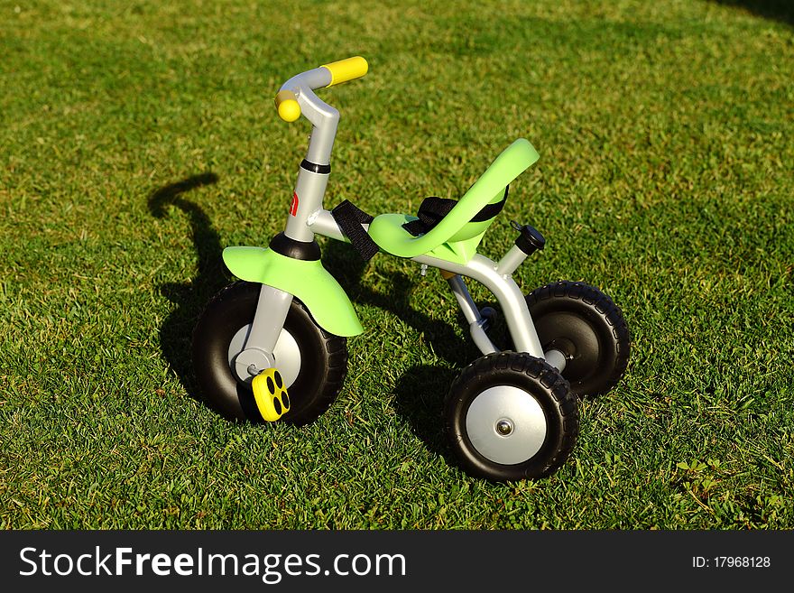 Children tricycle in a green garden. Children tricycle in a green garden