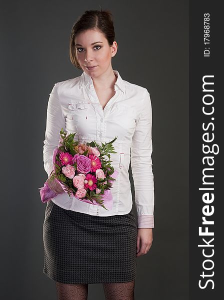 Young women with pink bouquet isolated on gray background