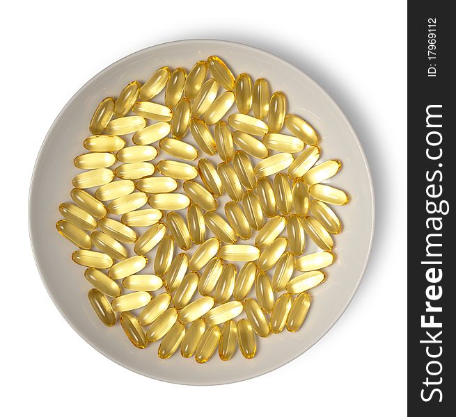 Gold medical capsules on plate isolated on white. Clipping path. Gold medical capsules on plate isolated on white. Clipping path