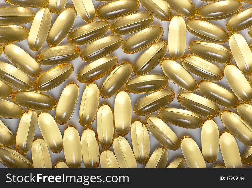 Gold medical capsules as abstract pattern in close up. Gold medical capsules as abstract pattern in close up