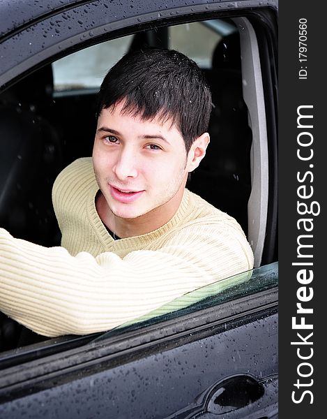 Happy young man smiling from his car