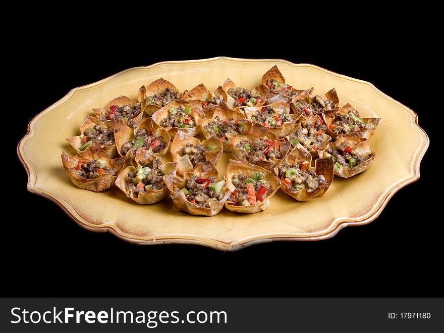 A platter of won ton appetizers on a black background. A platter of won ton appetizers on a black background