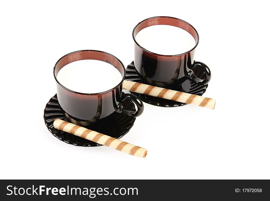 Two cups with milk and cookies. Isolated over white