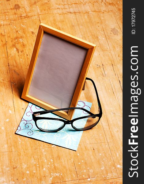 Modern photoframe with glasses on wooden background