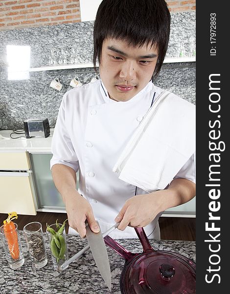 Asian young chef sharpening a knife brutally.