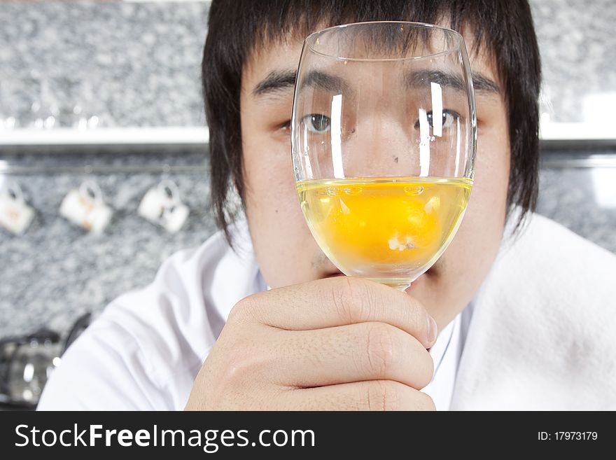 Asian young chef considering a glass of raw egg.