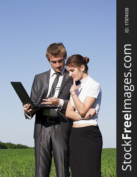 Portrait of businesswoman and businessman looking at monitor of laptop outdoor. Portrait of businesswoman and businessman looking at monitor of laptop outdoor