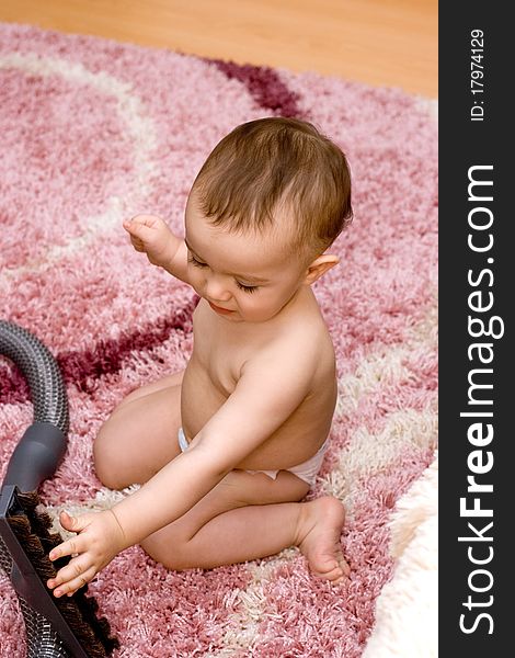 Cute caucasian baby with vacuum cleaner on the carpet