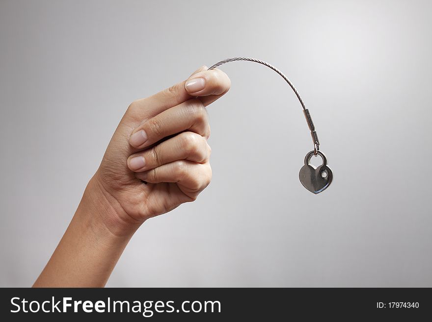 A hand holding a heart shape key-chain acting fishing. A hand holding a heart shape key-chain acting fishing.