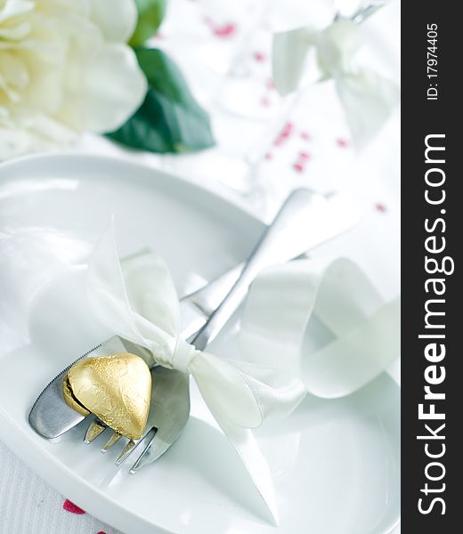 Fork and knife laying on plate with ribbon and heart. Fork and knife laying on plate with ribbon and heart