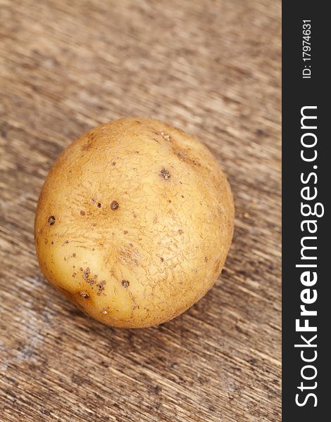 Single potato on a wooden background
