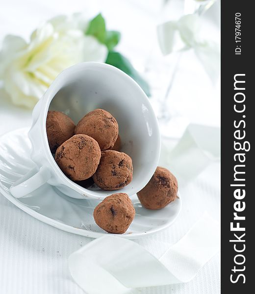 Chocolate candy in cup with flower on background