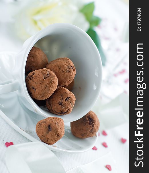 Chocolate candy in cup with flower on background