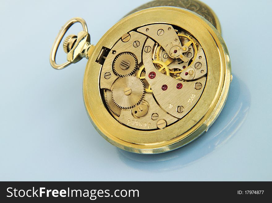 Clockwork pocket watch on the light blue background