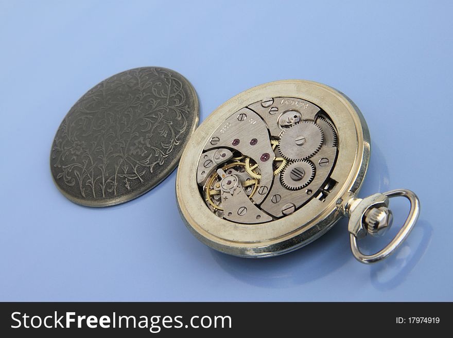 Clockwork pocket watch on the light blue background. Clockwork pocket watch on the light blue background