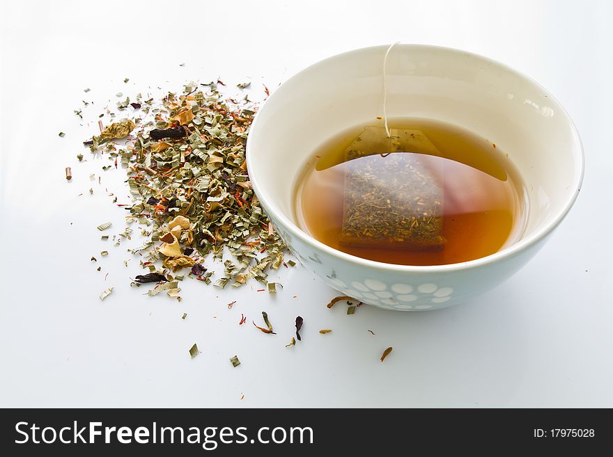 Herbal tea leves and with a tea cup on white table