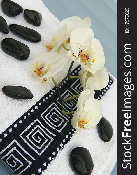 Massage stones, orchid and a black-white towel. Massage stones, orchid and a black-white towel.