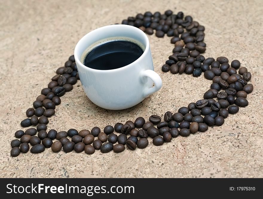 Cup of coffee sorrounded by a heart shape made from coffee beans. Cup of coffee sorrounded by a heart shape made from coffee beans