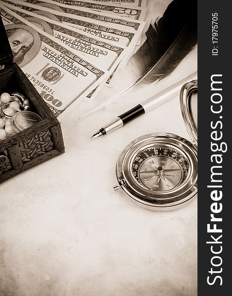 Dollar, pen and feather at table on sepia