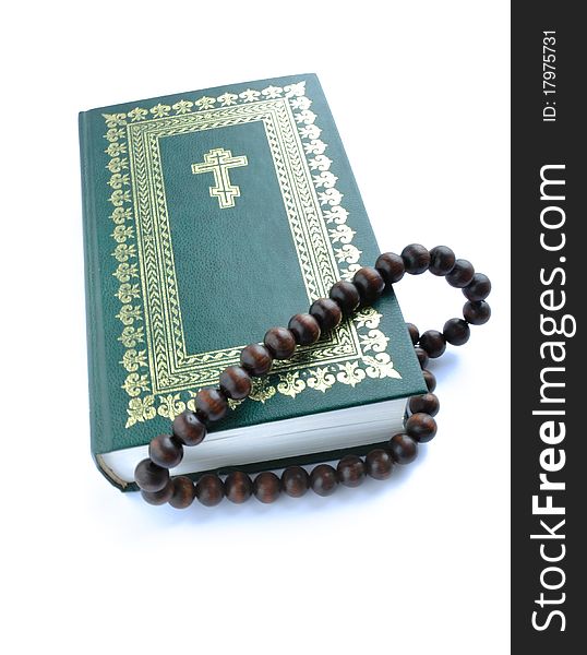 Closing bible of the green colour with gold(en) ornament and rosary beads overhand. Closing bible of the green colour with gold(en) ornament and rosary beads overhand