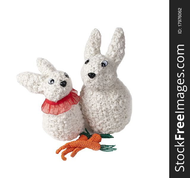 Two isolated toy hares with three carrots